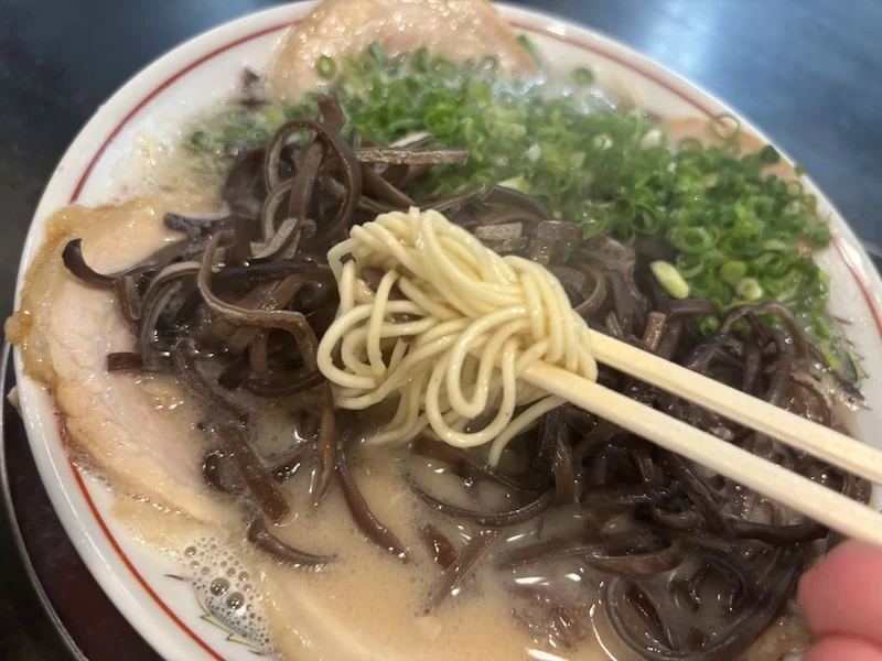 箸で持ち上げた博多ラーメンの極細ストレート麺