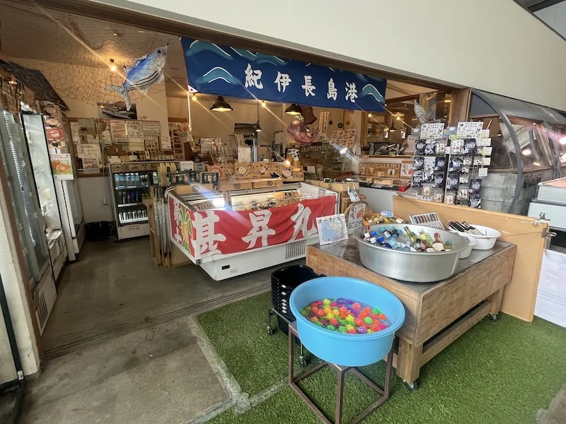 紀伊長島港ののれんと大漁旗が掲げられた第十八甚昇丸の店構え